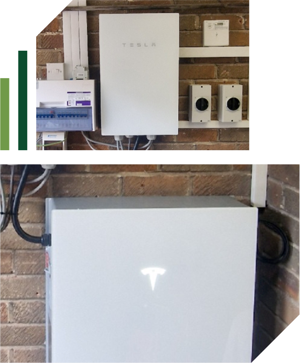 A Tesla Powerwall battery system is mounted on a brick wall, alongside electrical panels and wiring. The illuminated Tesla logo highlights this modern addition to your home electrical setup, installed with expert electrical contractor services. | Green View Projects